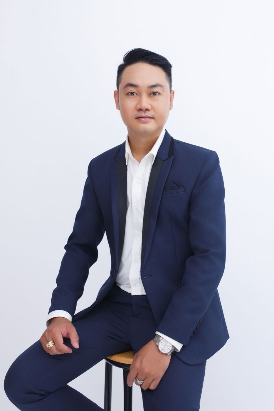 Daniel Tran, a man in a navy suit and white shirt, against a white backdrop