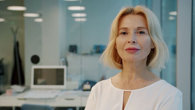 Elise M. Prescott, a woman with chin-length blonde hair in a white blouse, in an office