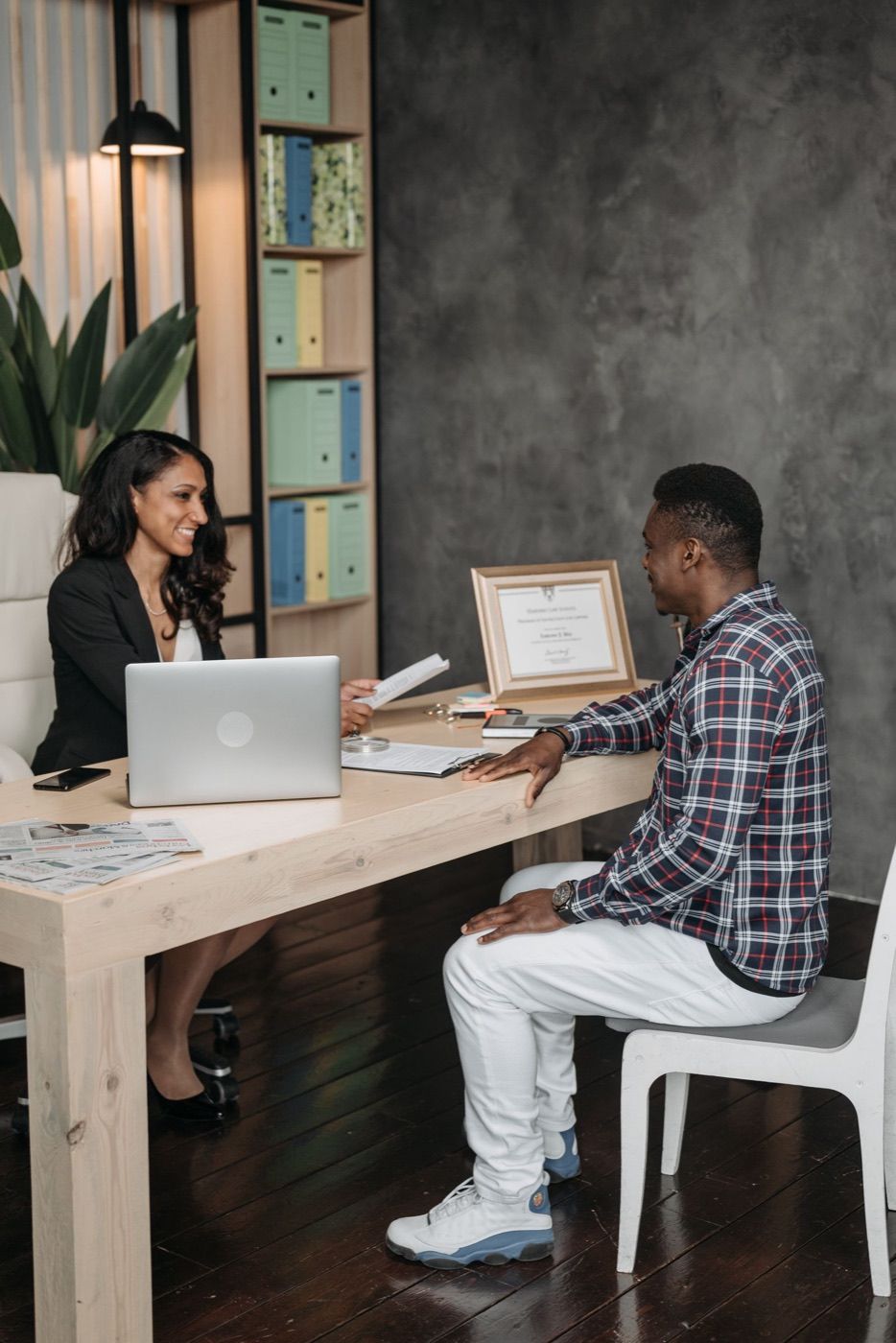An attorney at her desk reviewing papers with a client during a consultation