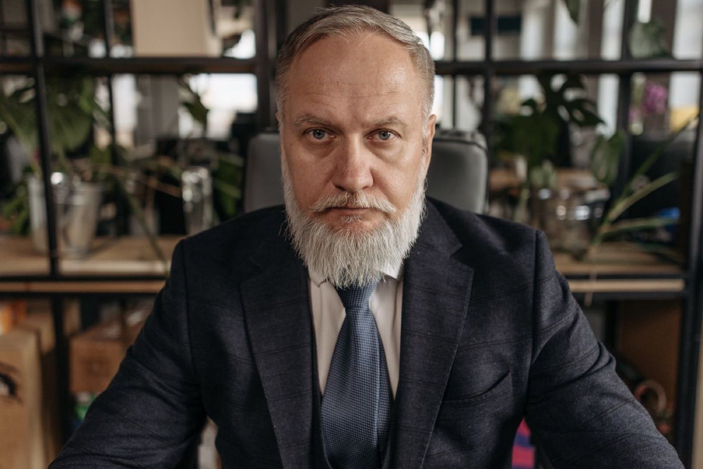 Walter Holloway, a gray-bearded man in a dark suit and tie, seated at his desk